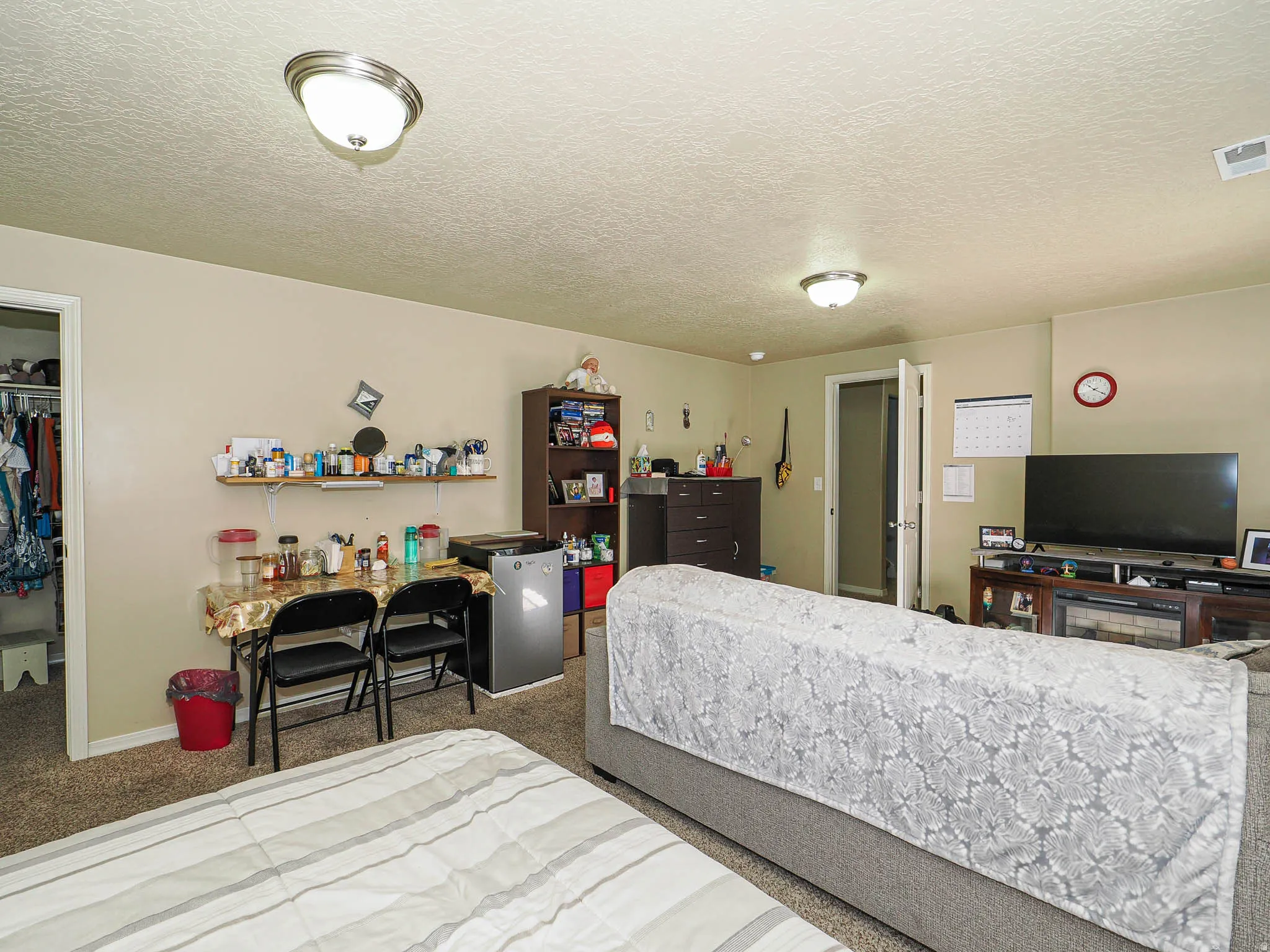 Carpeted room with a built-in wall shelf, flush mount lighting, and a closet with a bifold door