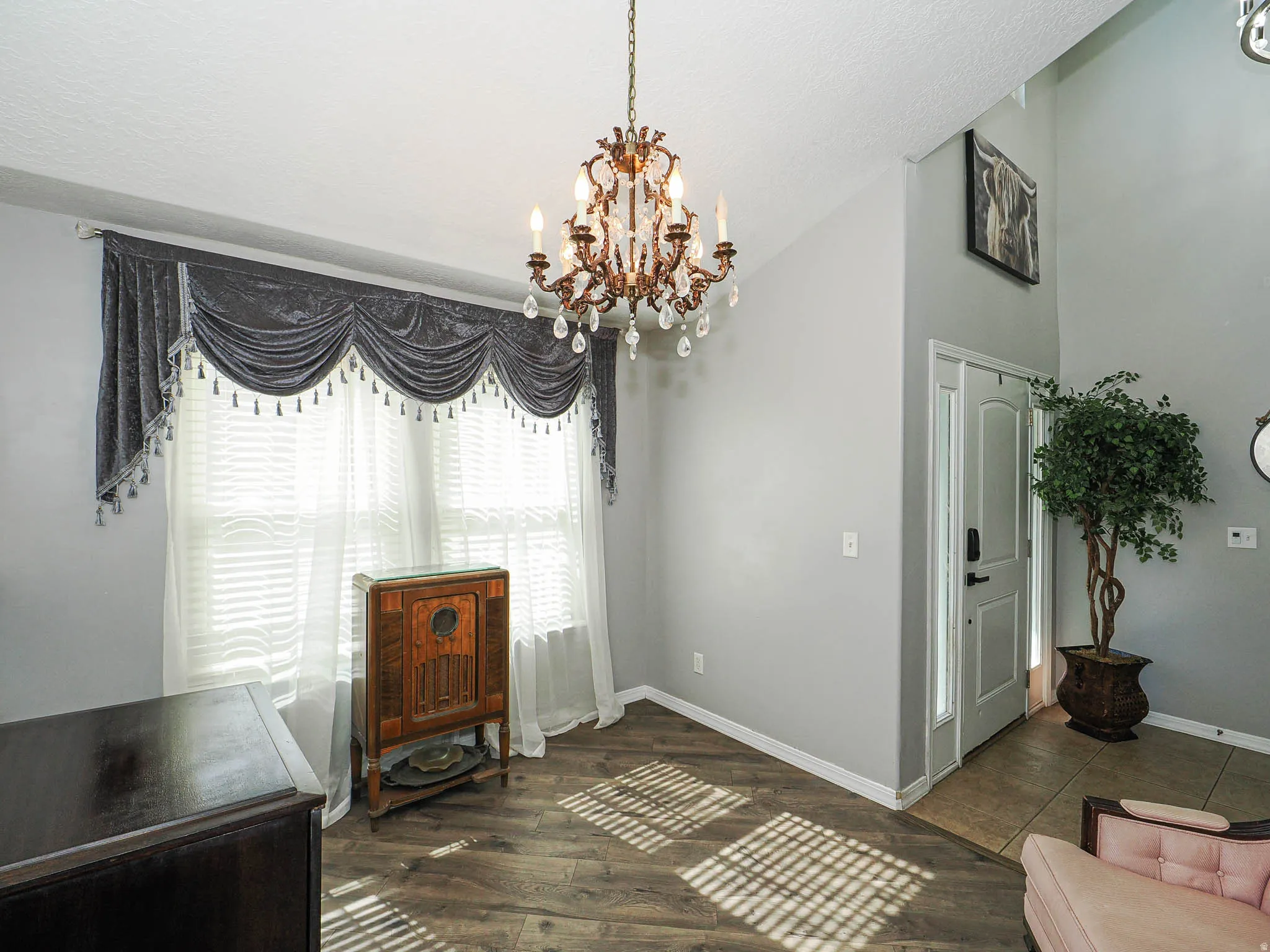 Entryway featuring a decorative chandelier with crystal accents, vaulted ceiling, and wood-finish flooring