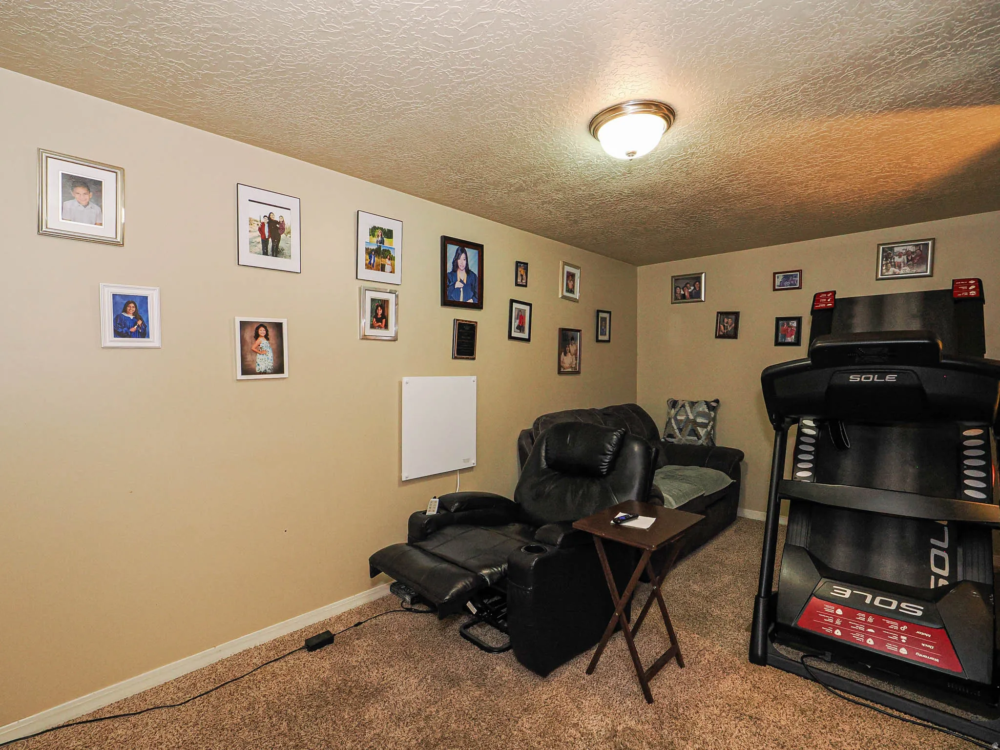 Carpeted room with neutral-toned walls, featuring a flush-mount ceiling light fixture, baseboard trim, and a textured ceiling finish