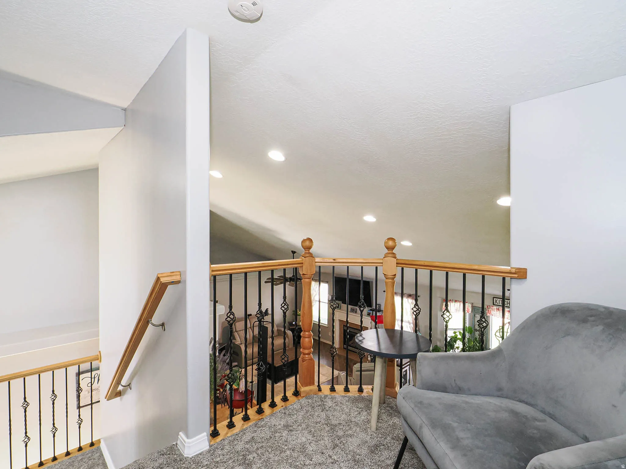 Upper-level landing featuring carpeting, a wood handrail, and wrought iron balusters
