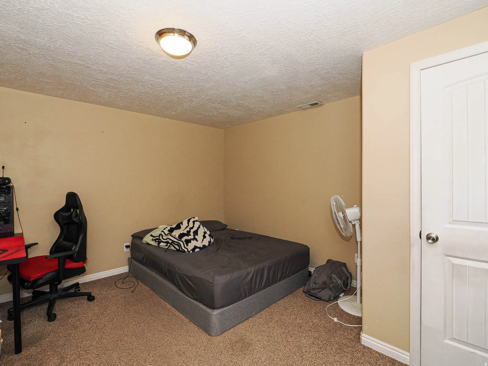 Neutral-toned room featuring a textured ceiling, a flush-mount ceiling light fixture, and brown carpet flooring
