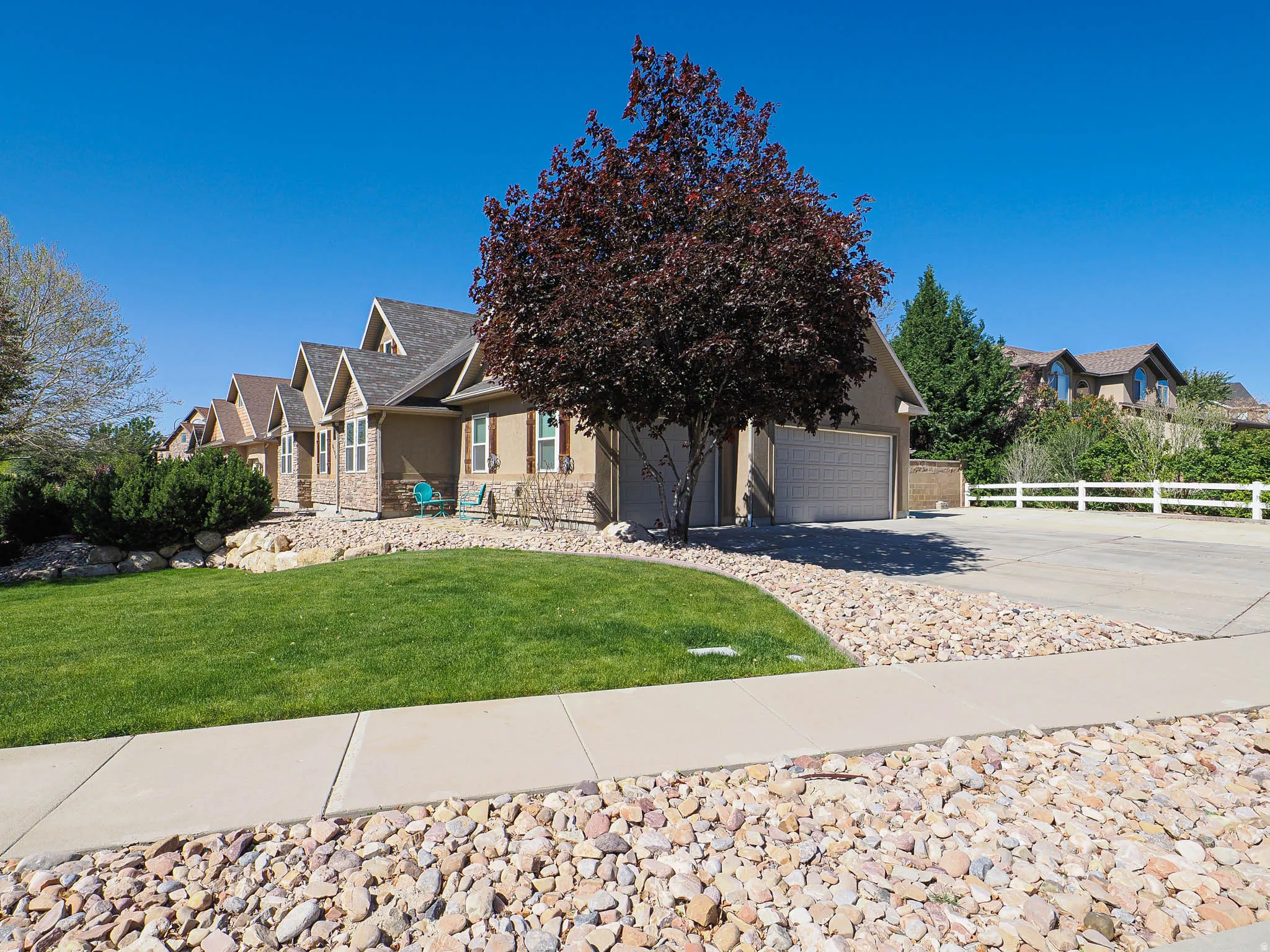 Two-story residence featuring a two-car garage, stone and stucco exterior, and gable roofline
