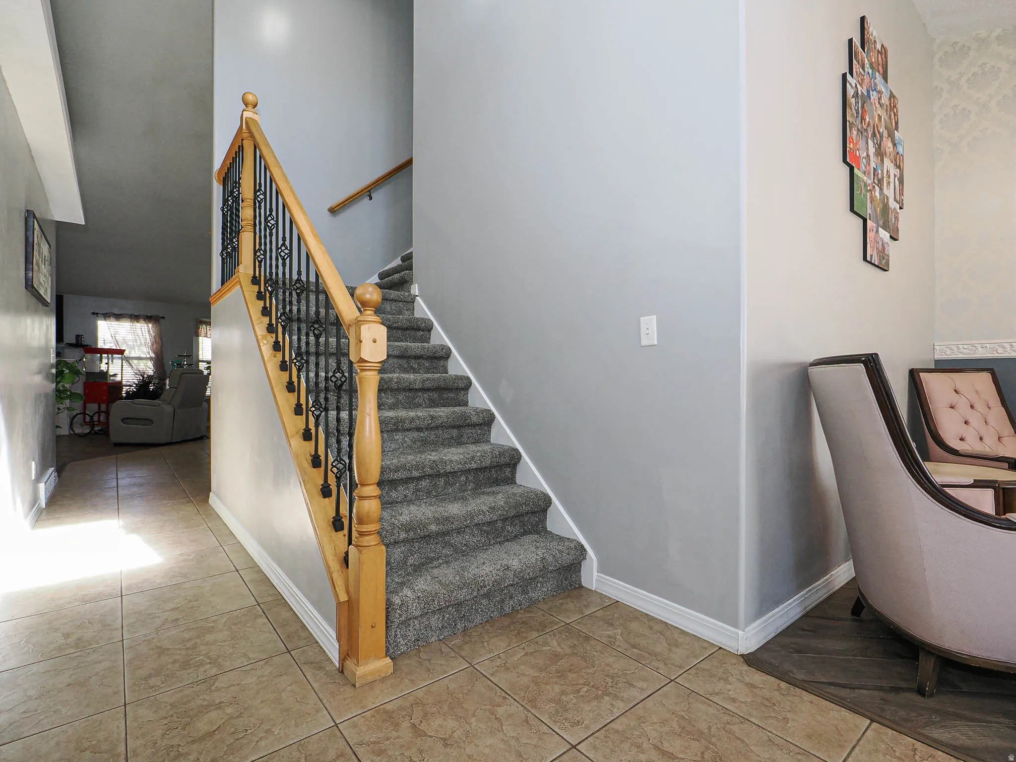 Staircase featuring wood handrails, wrought iron balusters, and carpeted treads