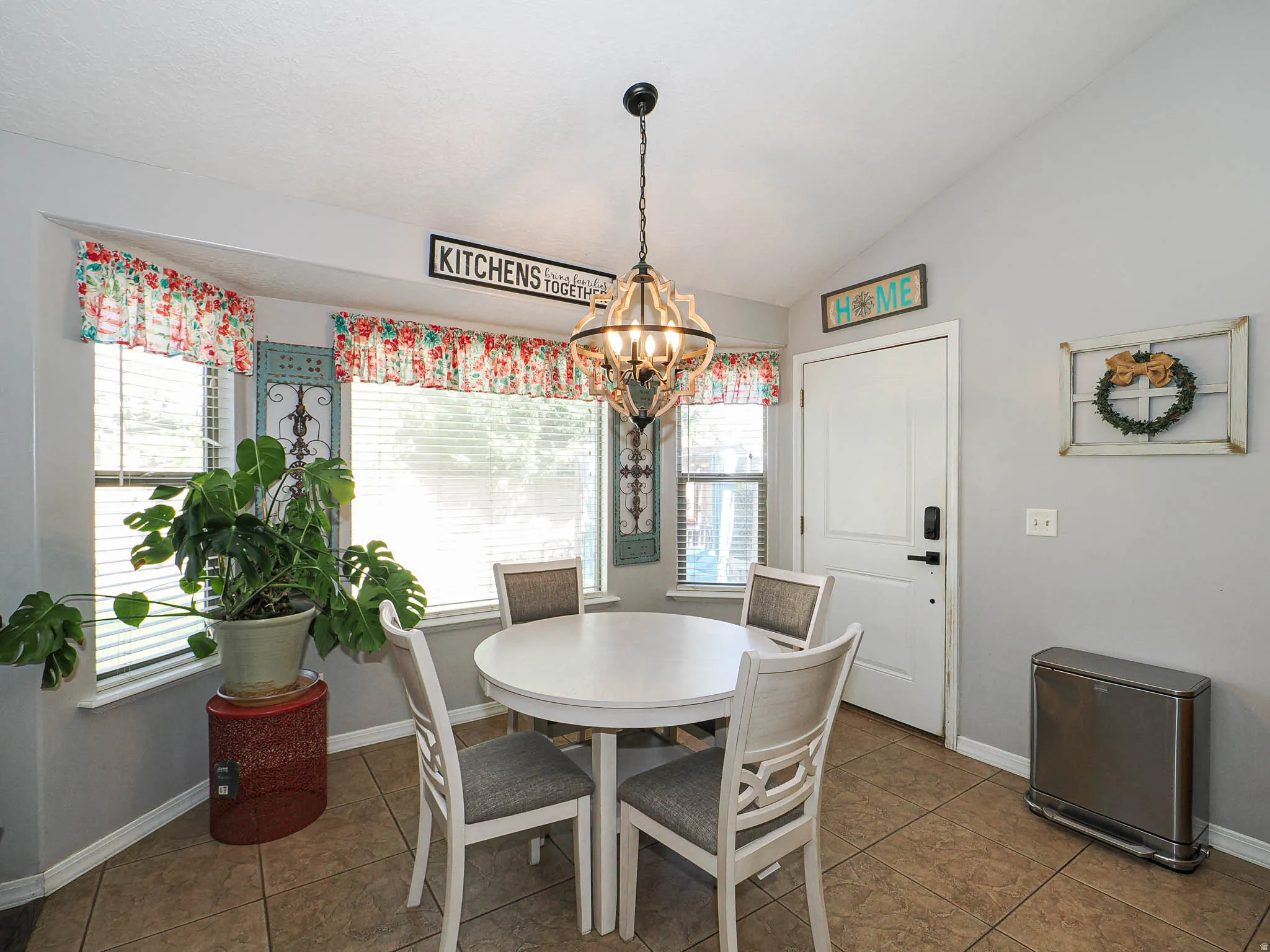 Dining area featuring a bay window, vaulted ceiling, tile flooring, and a pendant light fixture