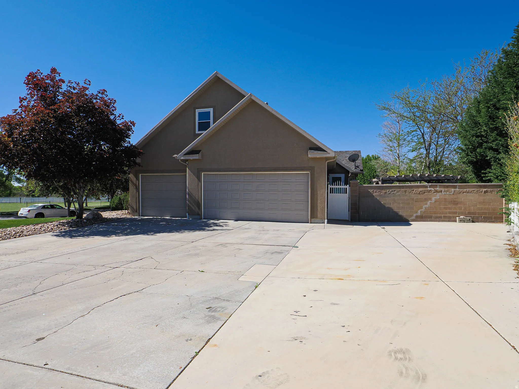 Stucco exterior residence featuring a two-car garage, pitched roofline, and a prominent front-facing window