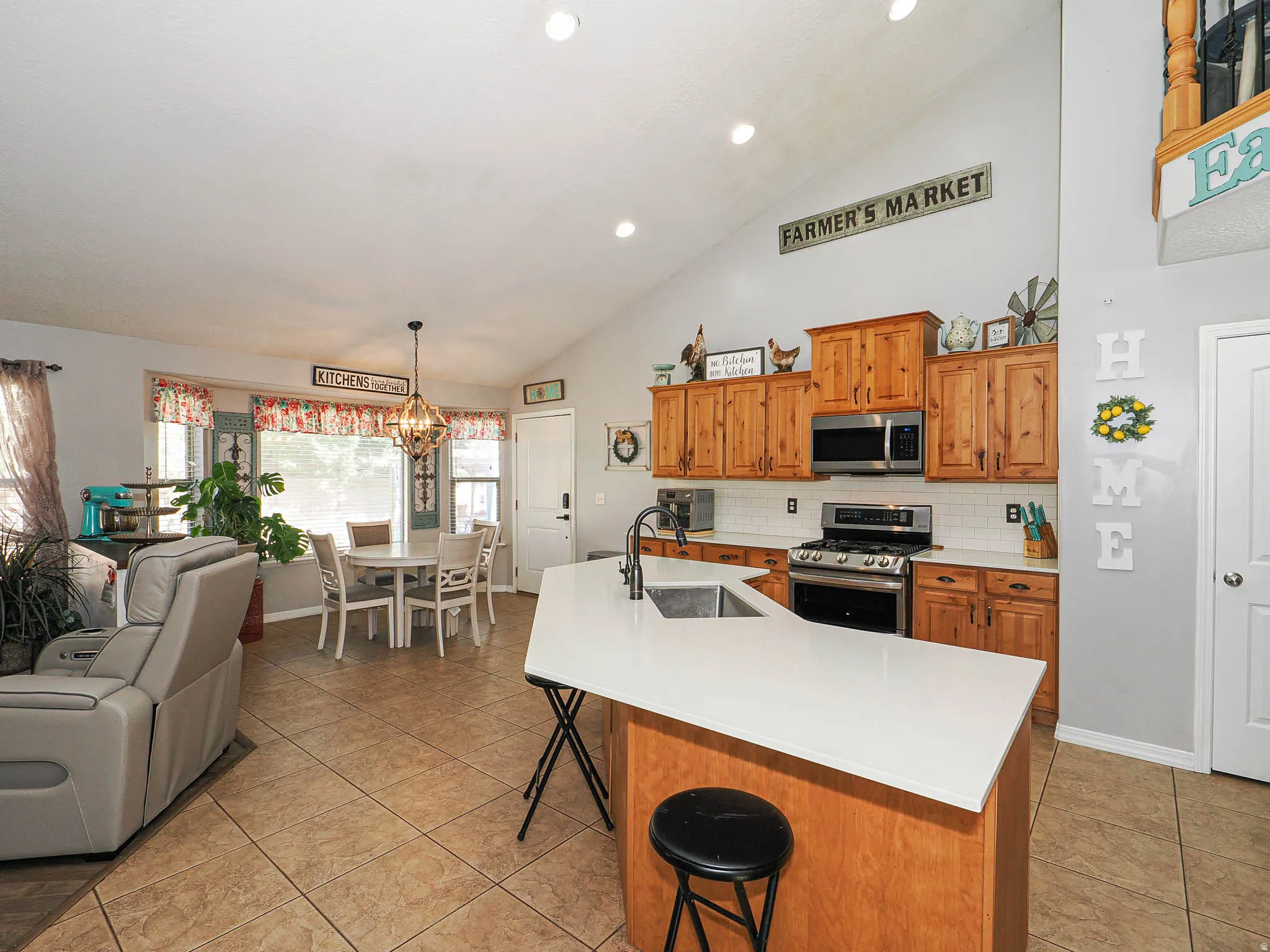 Kitchen featuring wood cabinetry, stainless steel appliances, white subway tile backsplash, and light-toned countertops
