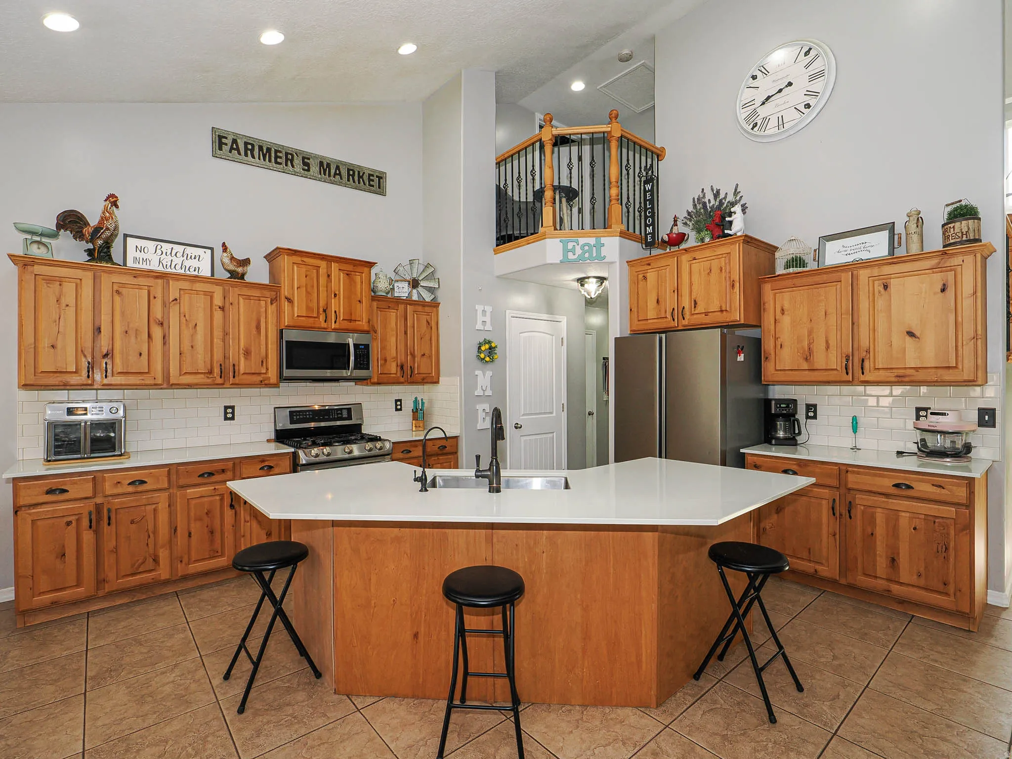 Kitchen featuring a multi-sided island with an undermount sink, wood cabinetry, stainless steel appliances, white subway tile backsplash, and recessed lighting