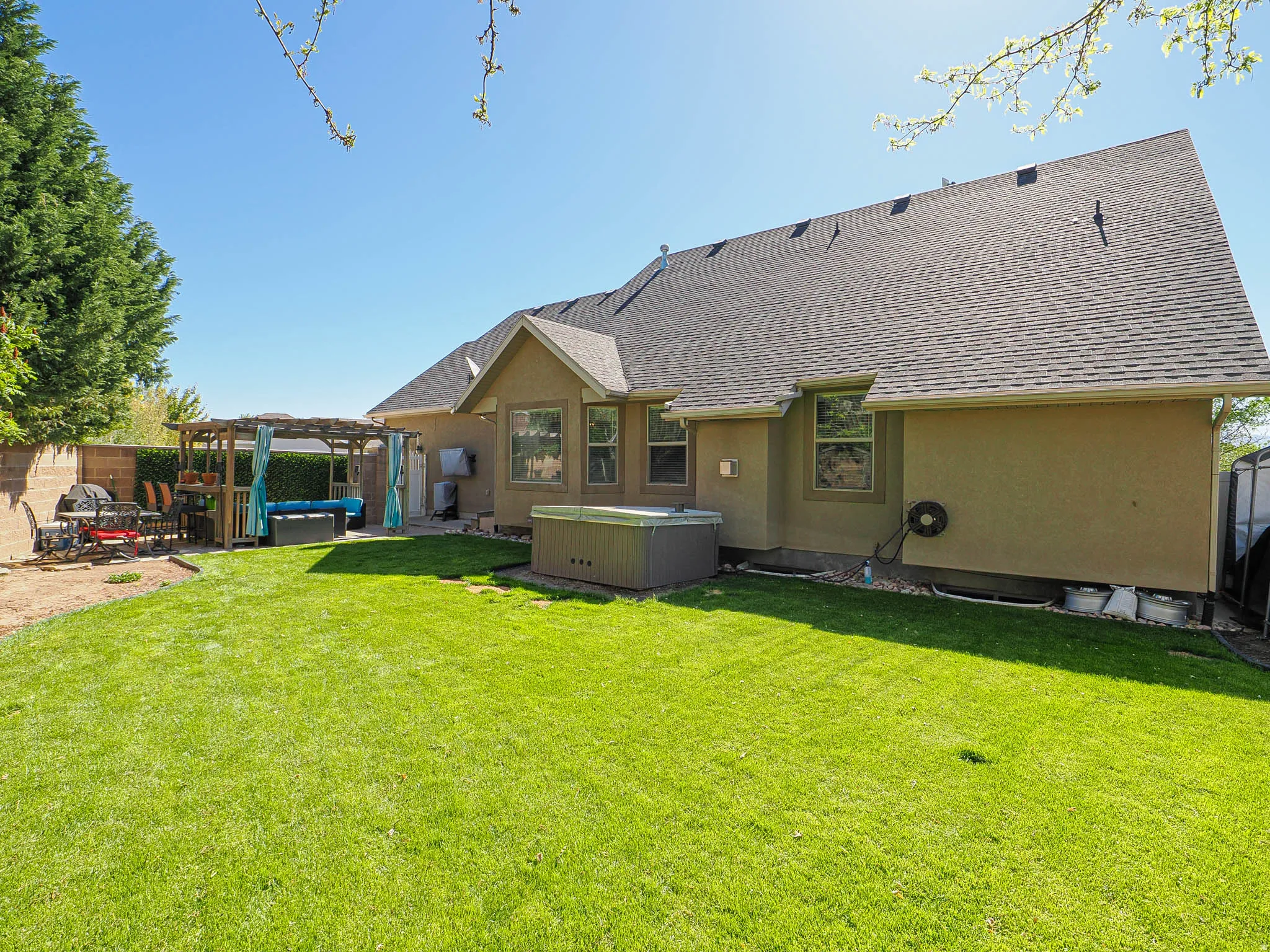 Expansive green lawn with a stucco exterior home featuring a dark shingle roof