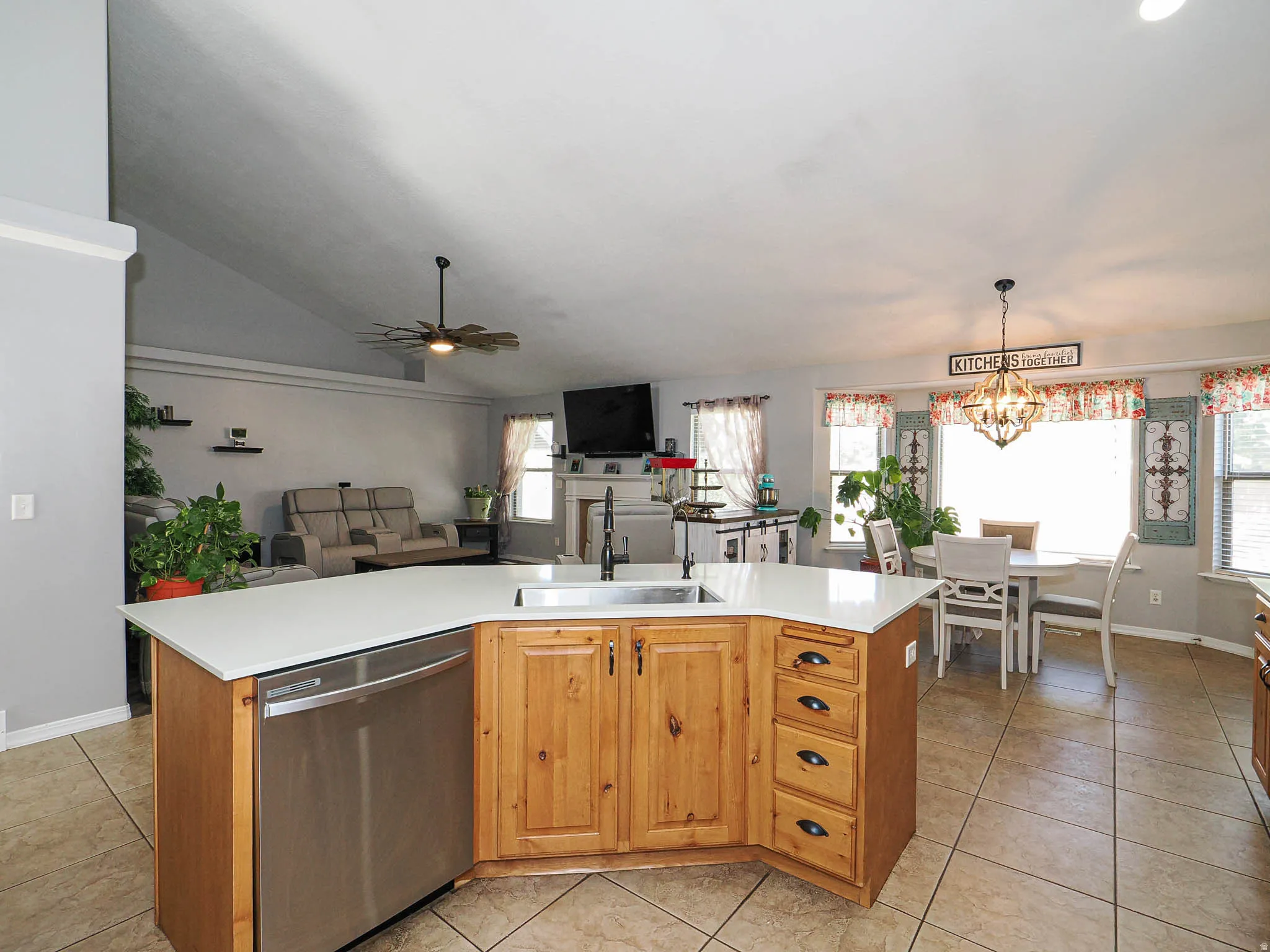 Kitchen island featuring wood cabinetry, integrated stainless steel dishwasher, and a sink with a gooseneck faucet