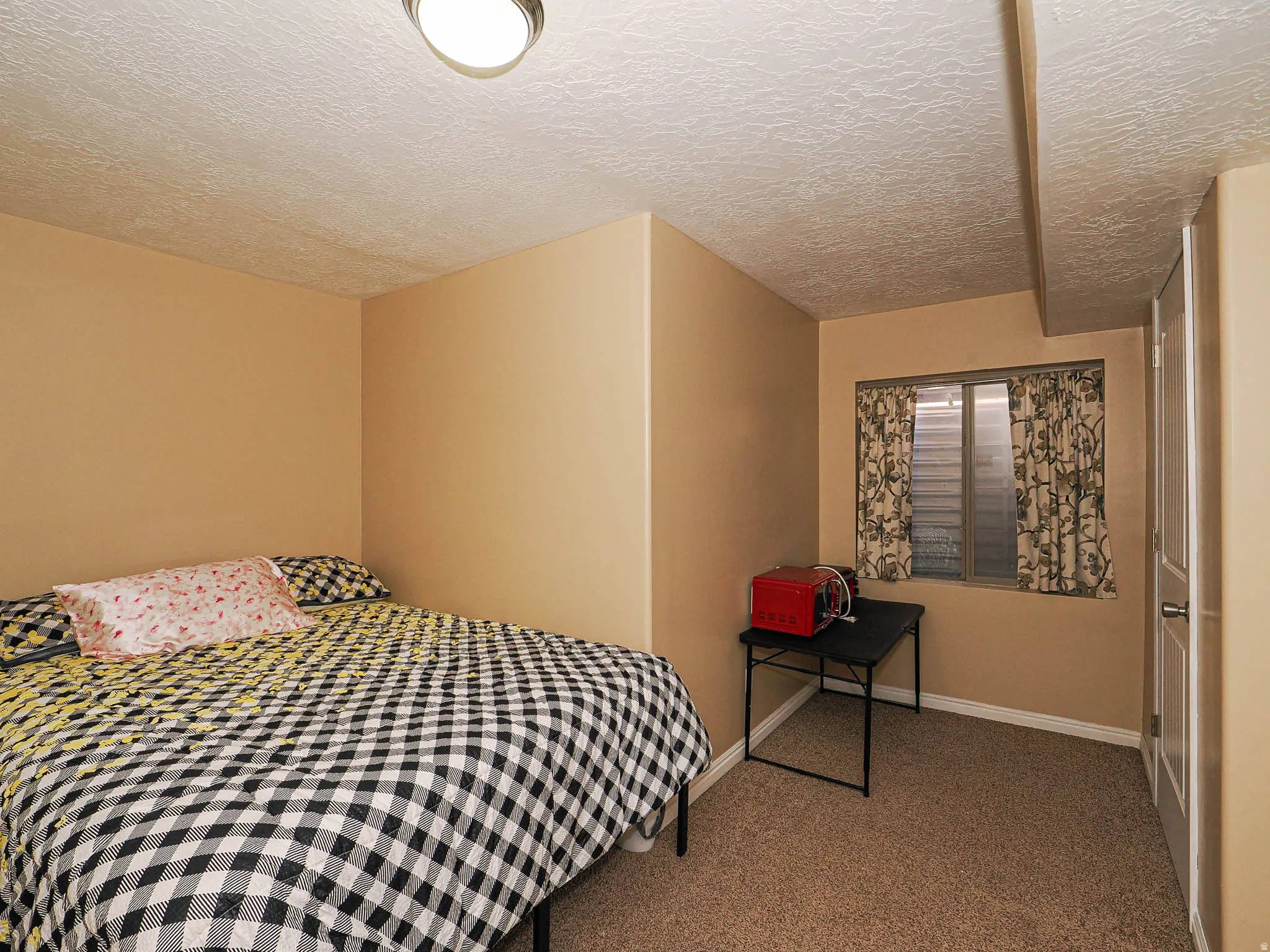 Carpeted room with a textured ceiling and neutral-toned walls