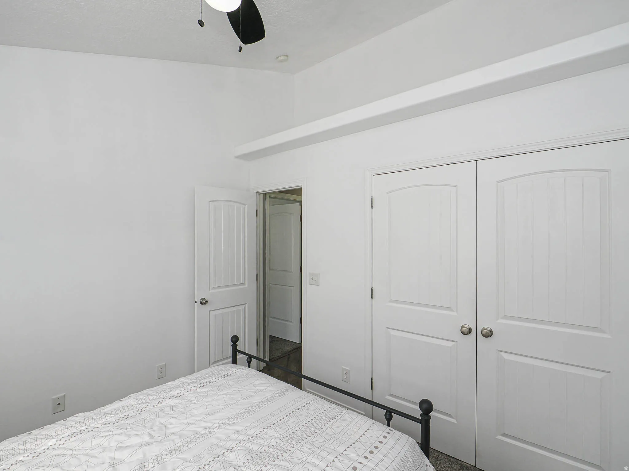 Vaulted ceiling with ceiling fan, white paneled doors, and light-colored wall-to-wall carpeting