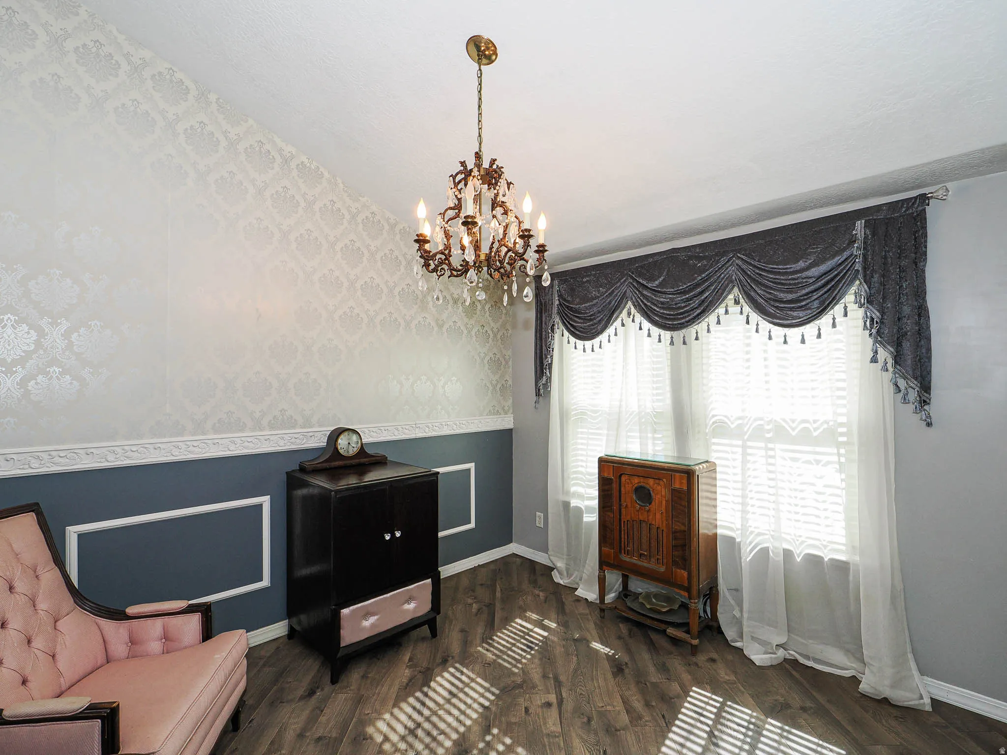 Interior space featuring an ornate chandelier, textured accent wall, and wood-finish flooring