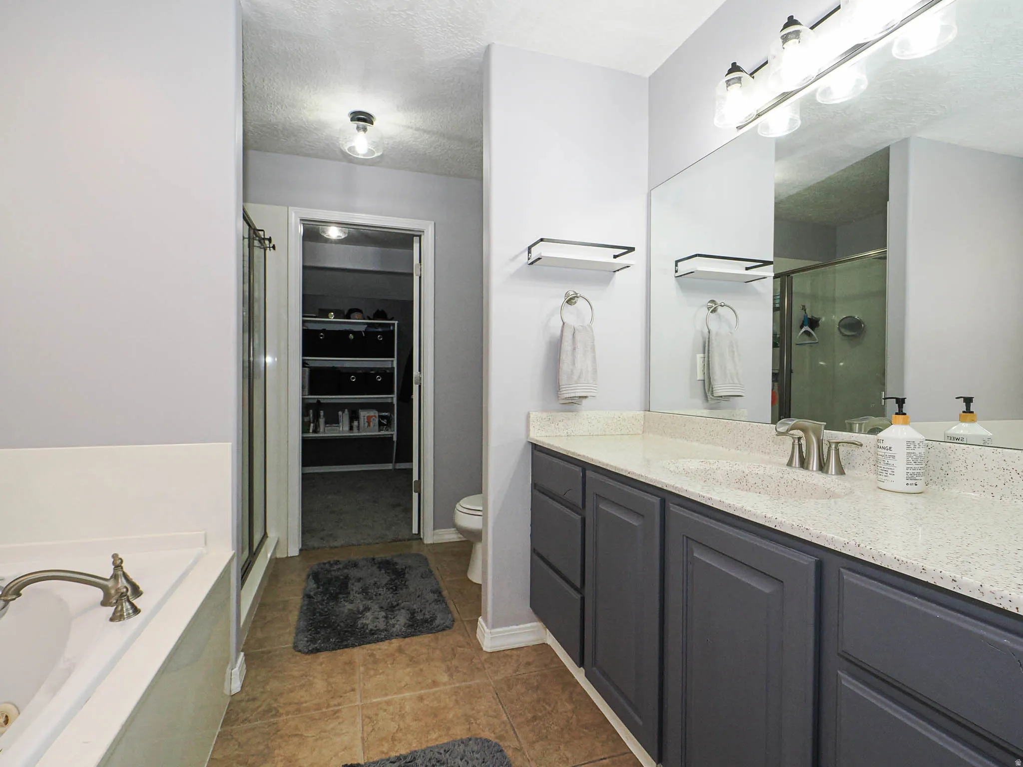 Bathroom featuring a dual vanity with light-toned countertop, brushed nickel fixtures, and dark gray cabinetry