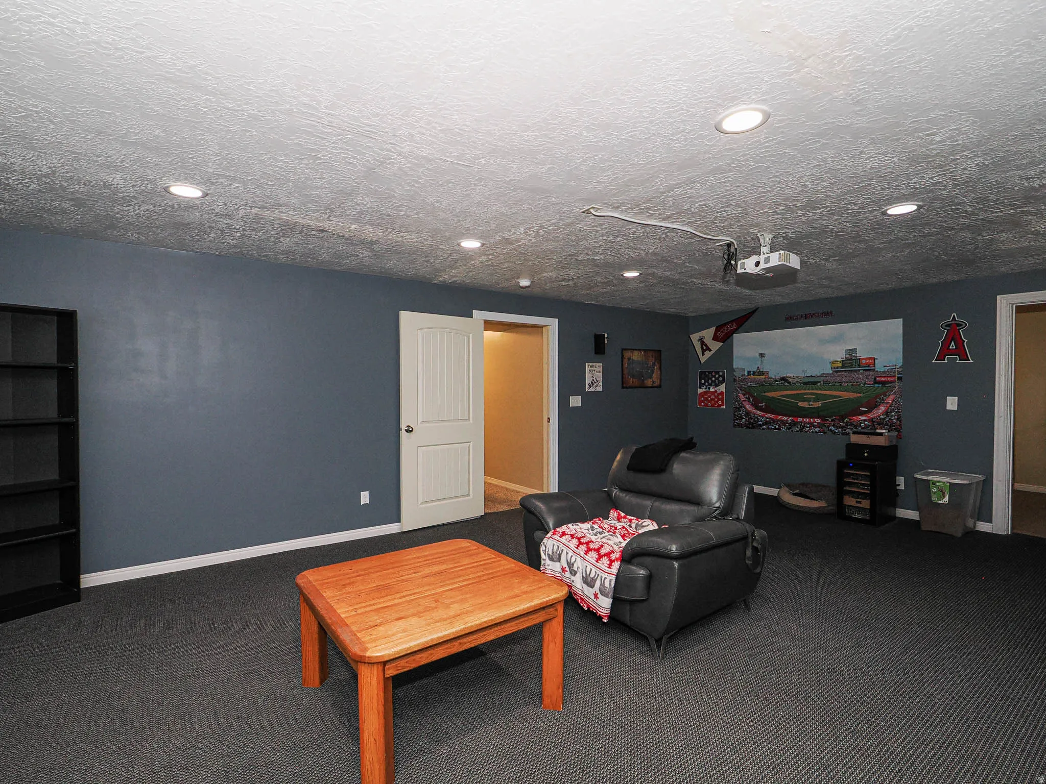 Recessed lighting illuminates this room featuring dark gray walls and textured carpeting