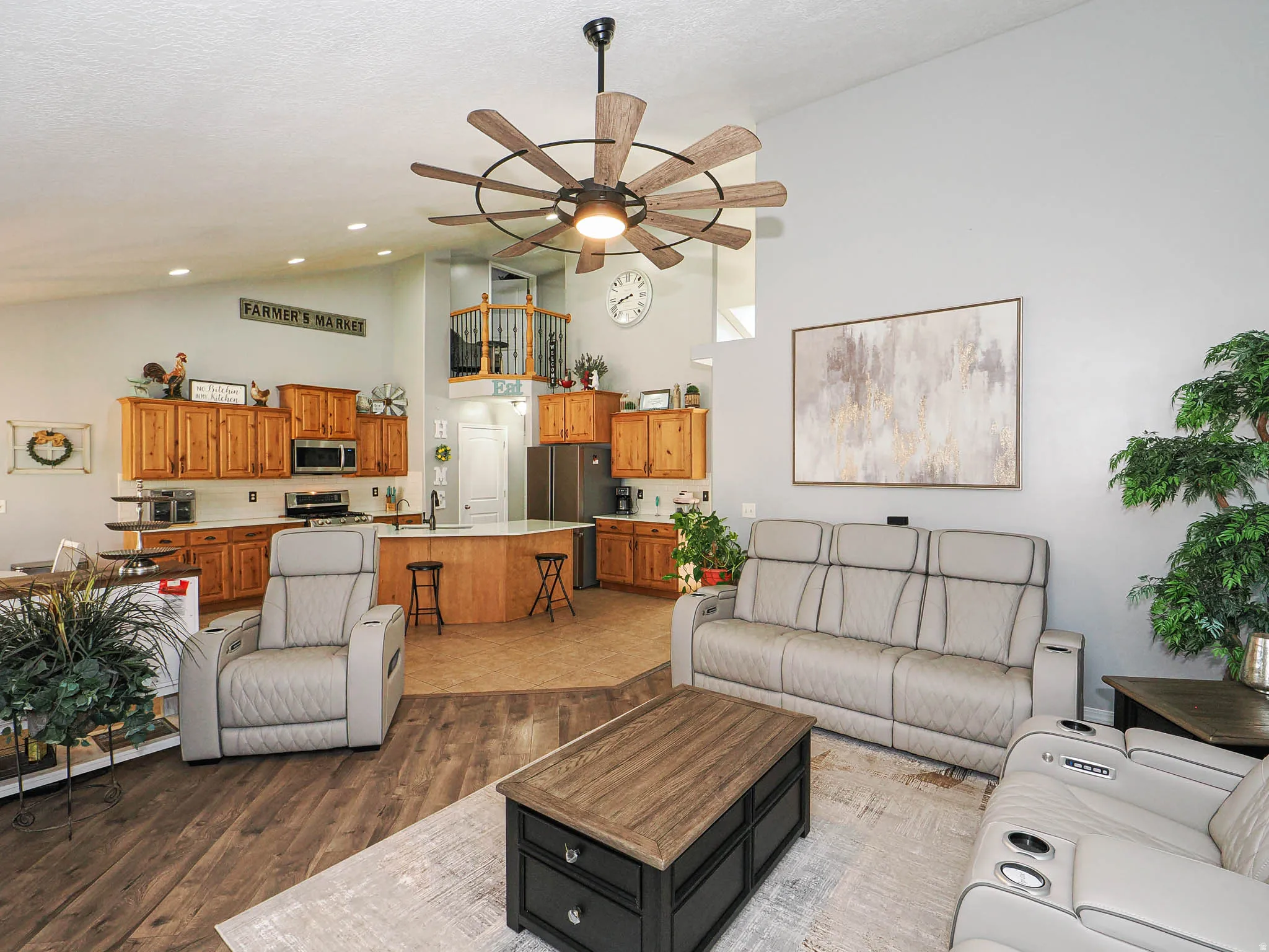 Spacious living area featuring wood-finish flooring, a large ceiling fan, and high ceilings