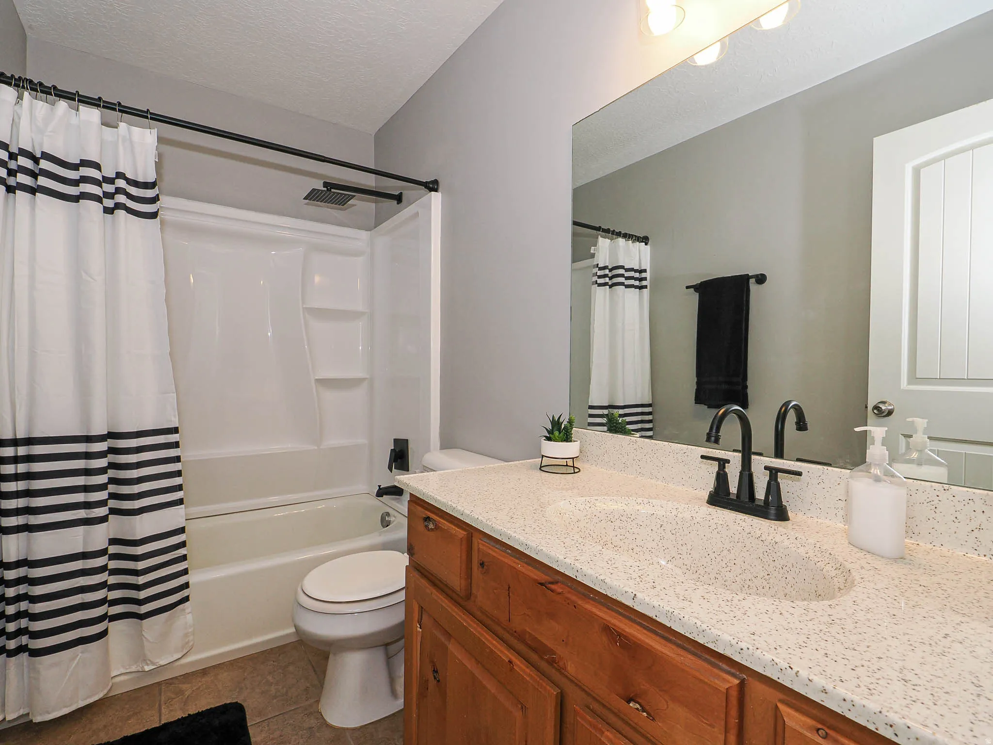 Bathroom featuring a wood vanity with a speckled countertop, integrated sink, and black faucet