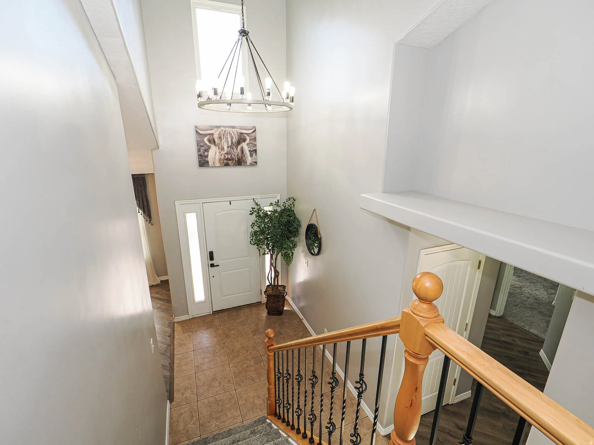 Two-story foyer featuring a contemporary chandelier, a transom window, and a tile floor