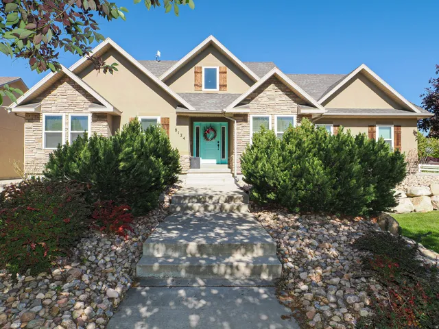 Stone and stucco exterior featuring multiple gables, a teal front door, and decorative wood shutters