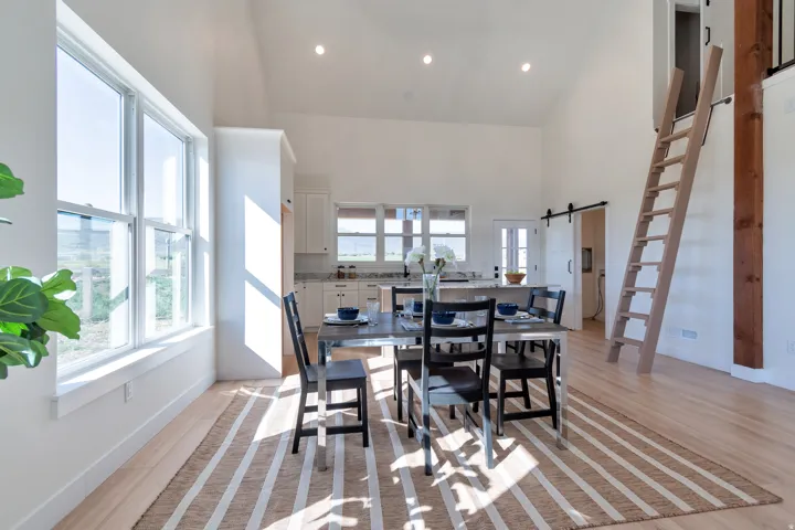 Open-concept dining area featuring vaulted ceilings, wood-finish flooring, recessed lighting, and expansive windows