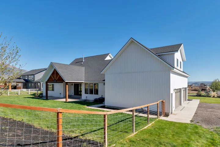 Modern farmhouse exterior with white board and batten siding, dark shingle roof, and a three-car garage