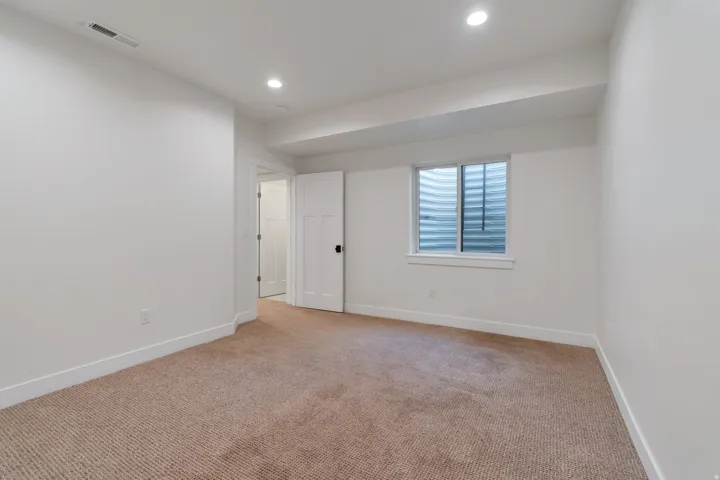 Carpeted room featuring recessed lighting, a white window frame with a window well, and a paneled interior door with black hardware