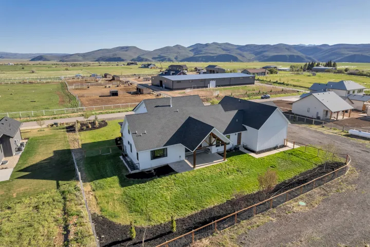 Modern farmhouse architectural style featuring a white exterior, dark shingle roof, and a covered patio with exposed wood beams