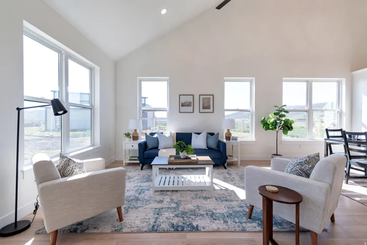 Vaulted ceilings enhance the bright living area, featuring multiple large windows, recessed lighting, and wood-finish flooring