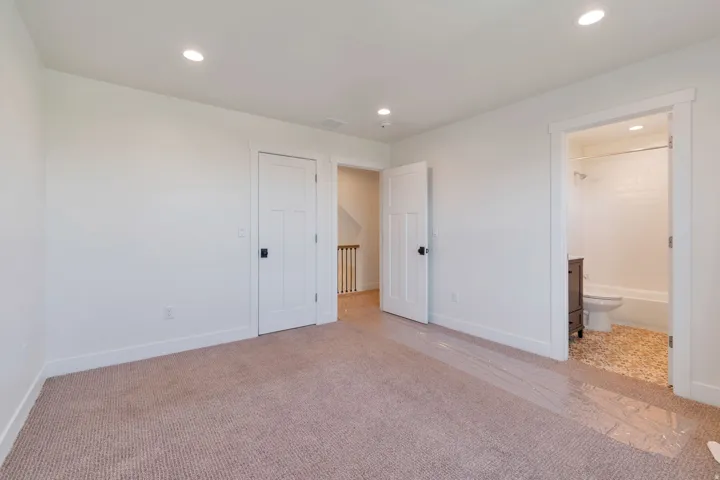 Neutral tone carpeting with white baseboards and walls