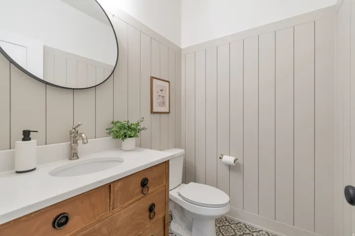Bathroom vanity featuring a wood-finish cabinet, white countertop, and under-mount sink with a brushed nickel faucet