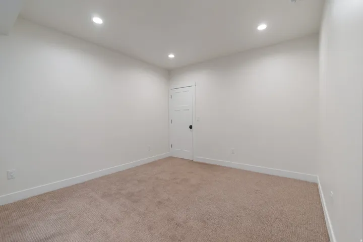 Neutral carpeted room featuring recessed lighting and a white paneled door