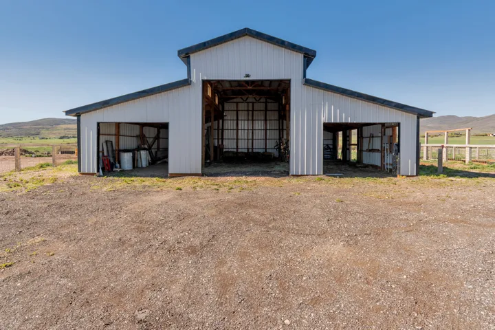 Metal-sided barn featuring a central open bay and two side sheds with sloped roofs