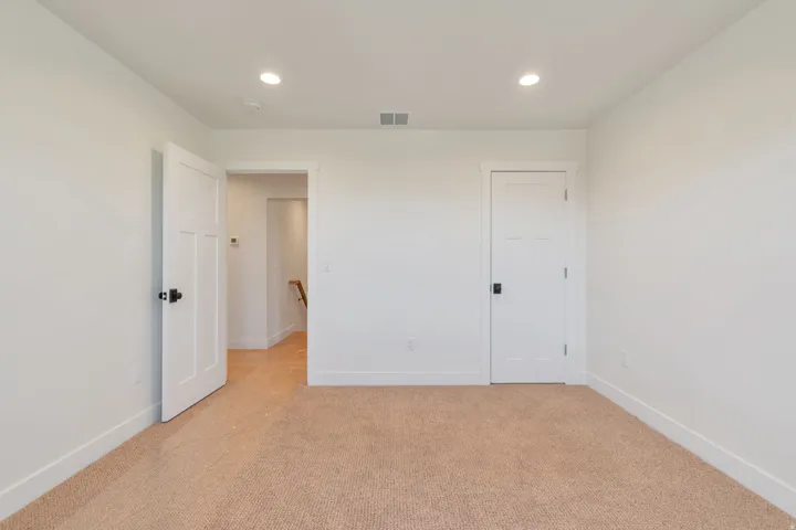 Neutral tone walls with recessed lighting and a textured carpet