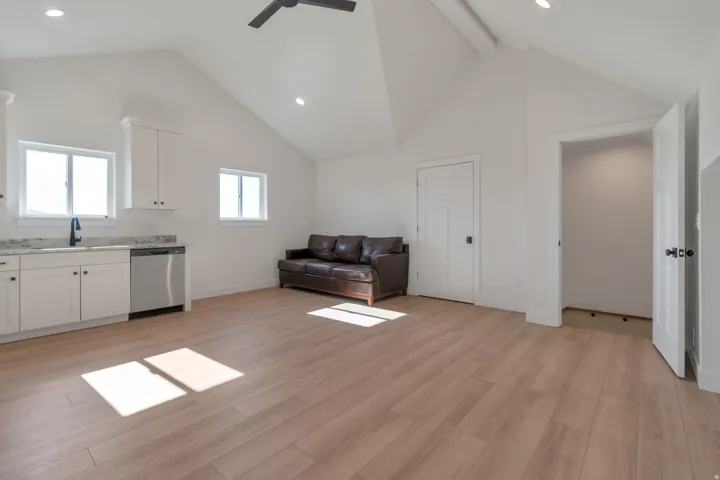 Spacious open-concept room featuring wood-finish flooring, vaulted ceilings, and recessed lighting