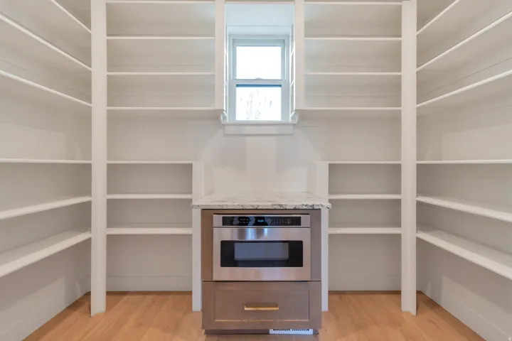 Built-in shelving flanking a microwave drawer and single window