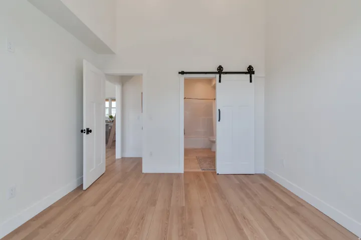 Vaulted ceilings frame this space, featuring wood-finish flooring and crisp white walls