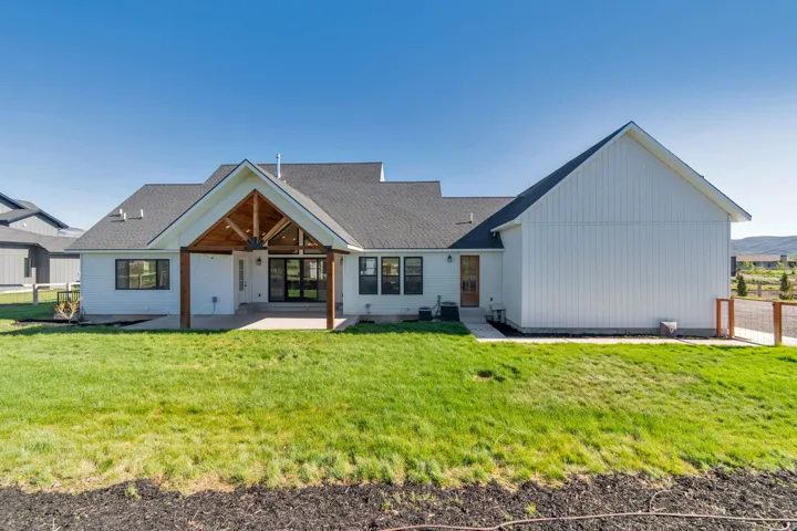 Expansive backyard featuring a covered patio with exposed wood beams and a vaulted ceiling