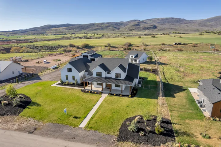 Modern farmhouse-style residence featuring a white exterior, black roof, and covered front porch with natural wood columns