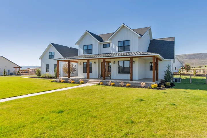 Modern farmhouse exterior featuring white board and batten siding, a dark pitched roof, and black-framed windows
