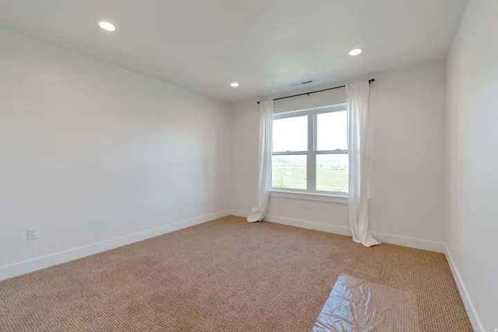 Spacious room featuring a large window, recessed lighting, and carpeted flooring