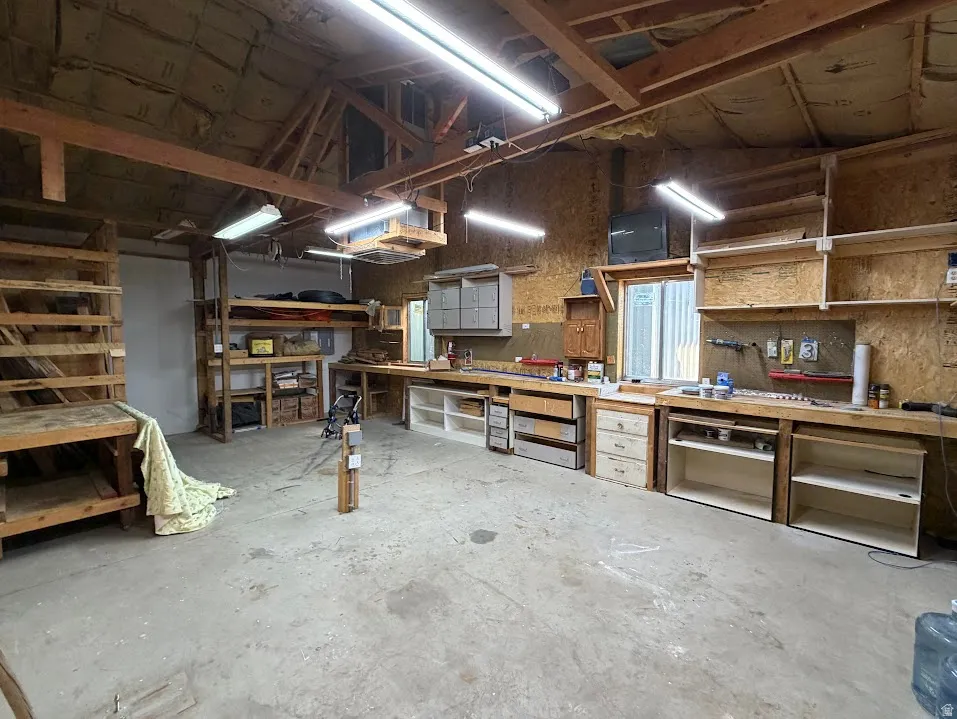 Spacious workshop featuring exposed wood beam ceilings and expansive workbench surfaces