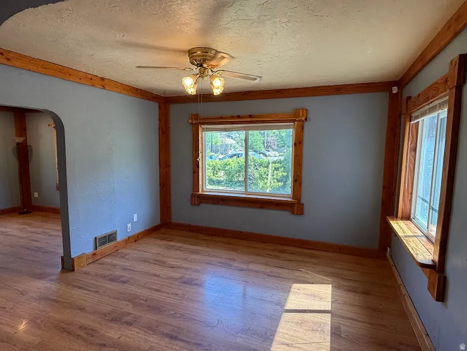 Spacious interior featuring wood-finish flooring, natural wood trim, and a ceiling fan with integrated lighting