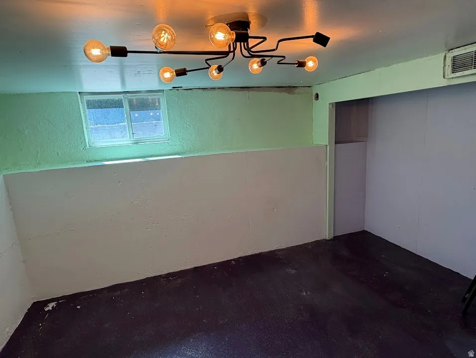 Interior space featuring a modern multi-bulb ceiling fixture, painted walls, and a small window