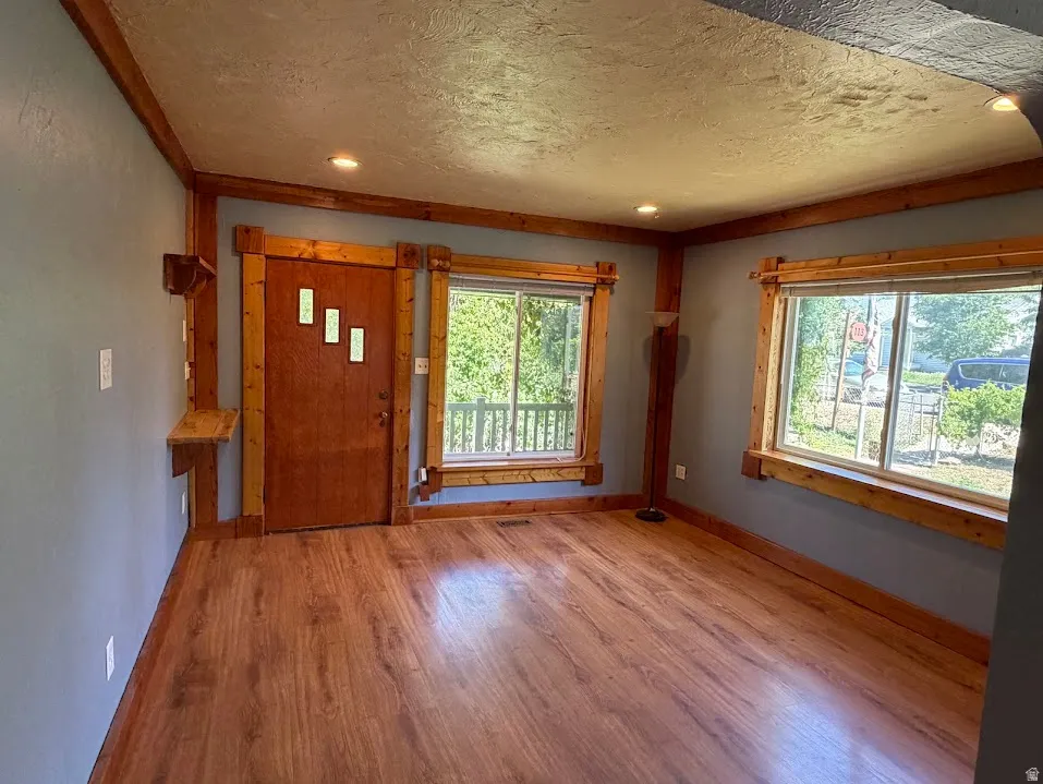 Spacious room featuring wood-finish flooring, light blue walls, and natural wood trim throughout