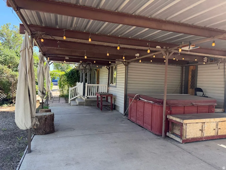 Covered patio with string lights, concrete flooring, and a built-in hot tub