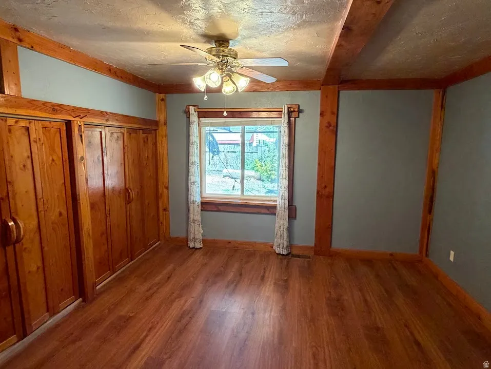 Room featuring wood-finish flooring, exposed wood beams, and built-in wood-paneled cabinetry