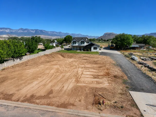 Cleared lot with graded earth, concrete curbing, and a visible fire hydrant