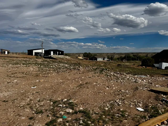 Expansive undeveloped lot featuring a natural, rocky terrain with scattered vegetation