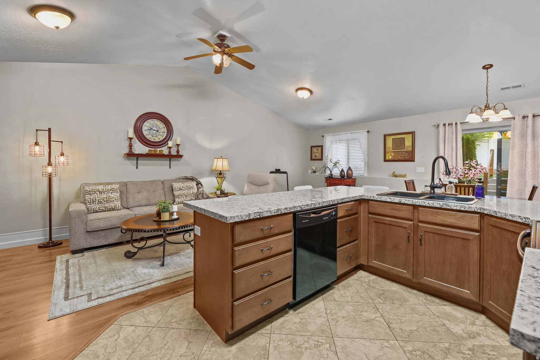 Open-concept living area featuring a kitchen island with granite-finish countertops, wood-finish cabinetry, and a built-in dishwasher