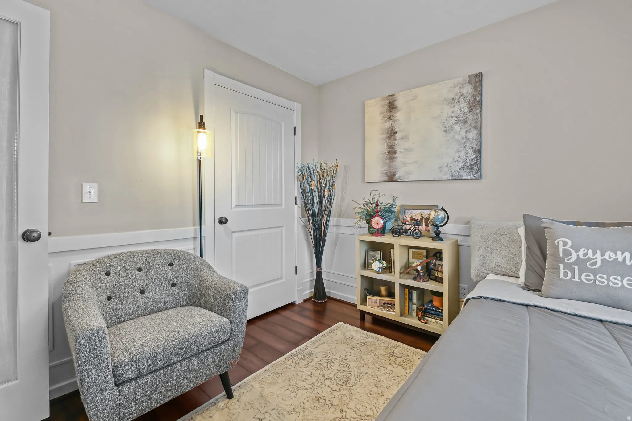 Room featuring rich wood-finish flooring, white wainscoting, and neutral-toned walls