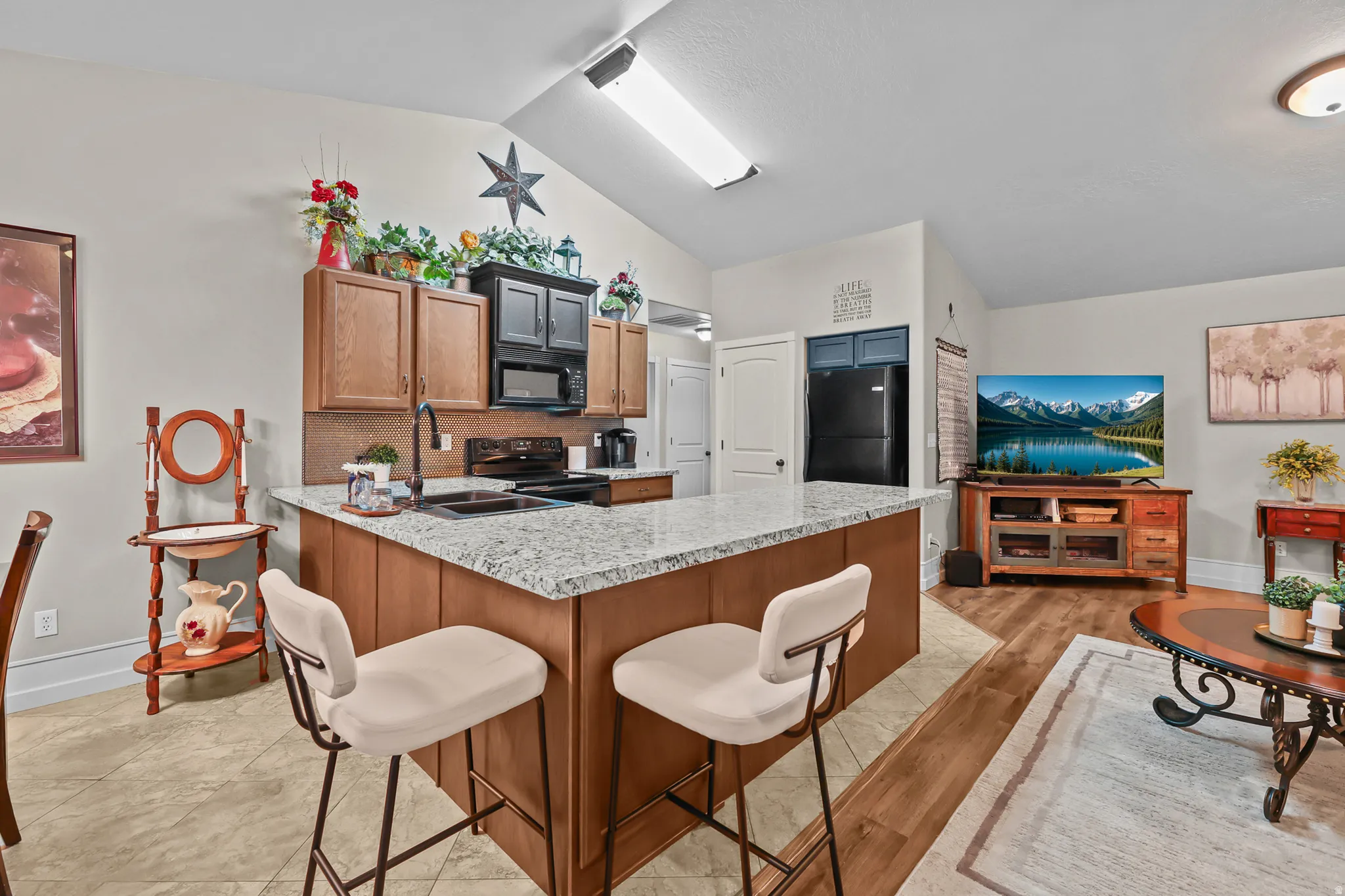Kitchen island featuring a granite-style countertop, wood-finish cabinetry, and an integrated double-basin sink with a matte black faucet